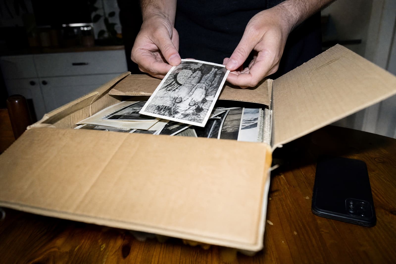 Manos que sacan una foto antigua en blanco y negro de una caja de cartón