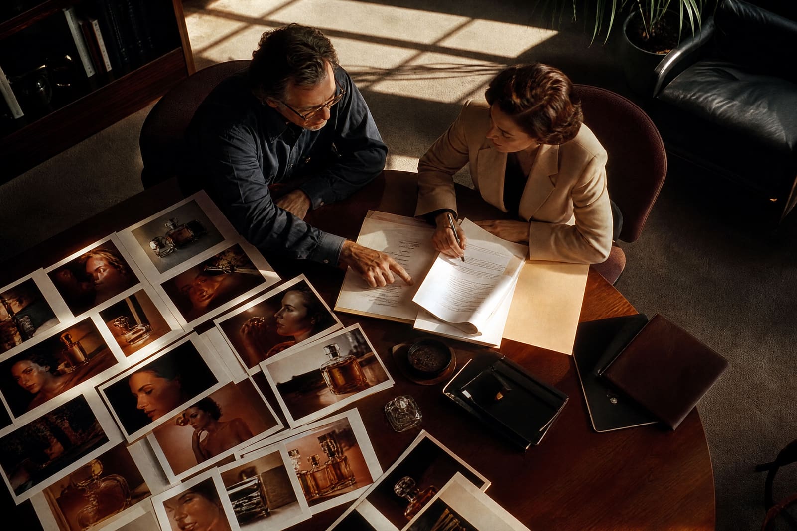 Un productor y una abogada repasan un contrato sobre una mesa llena de fotogramas impresos