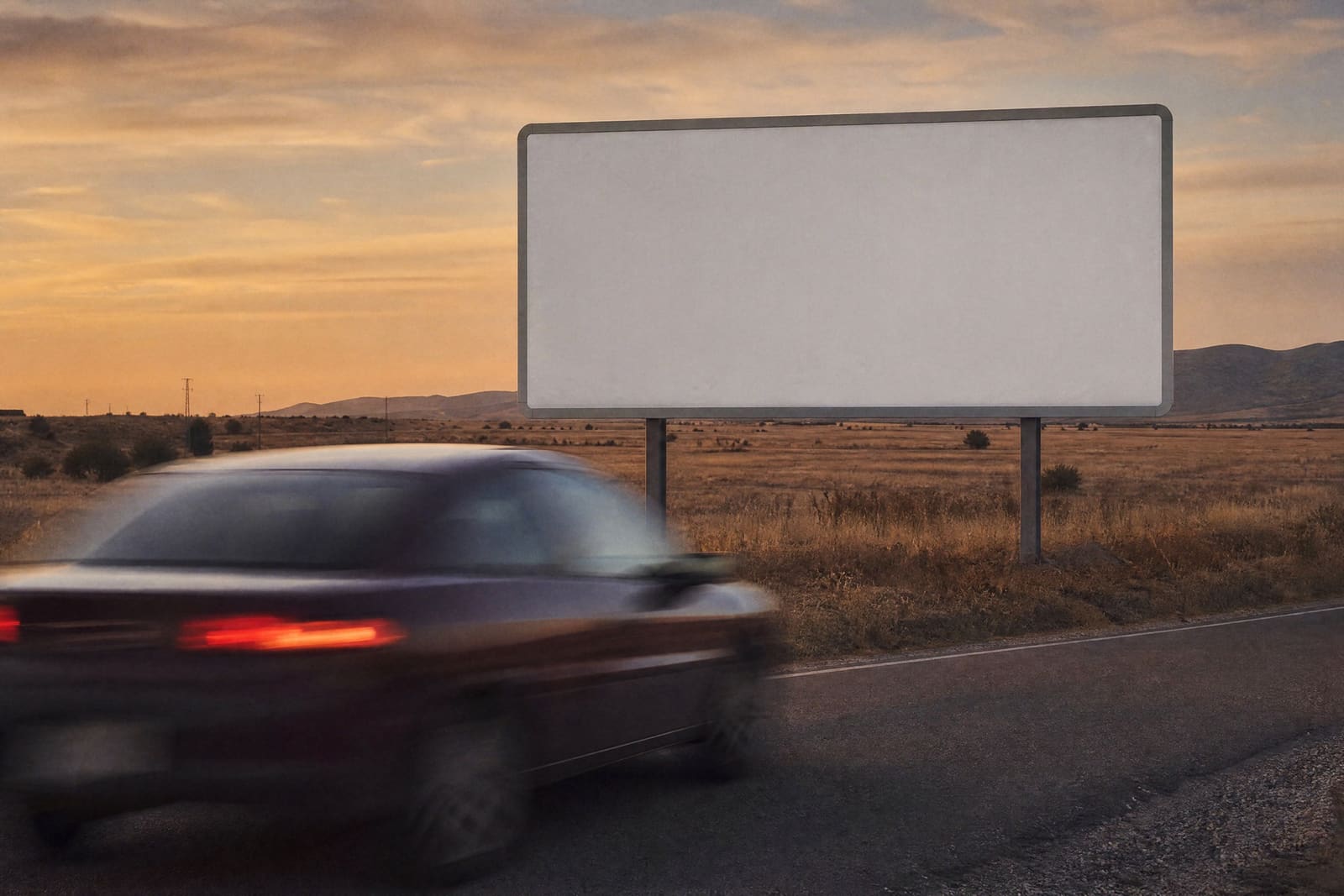 Una valla publicitaria en blanco junto a una carretera al atardecer