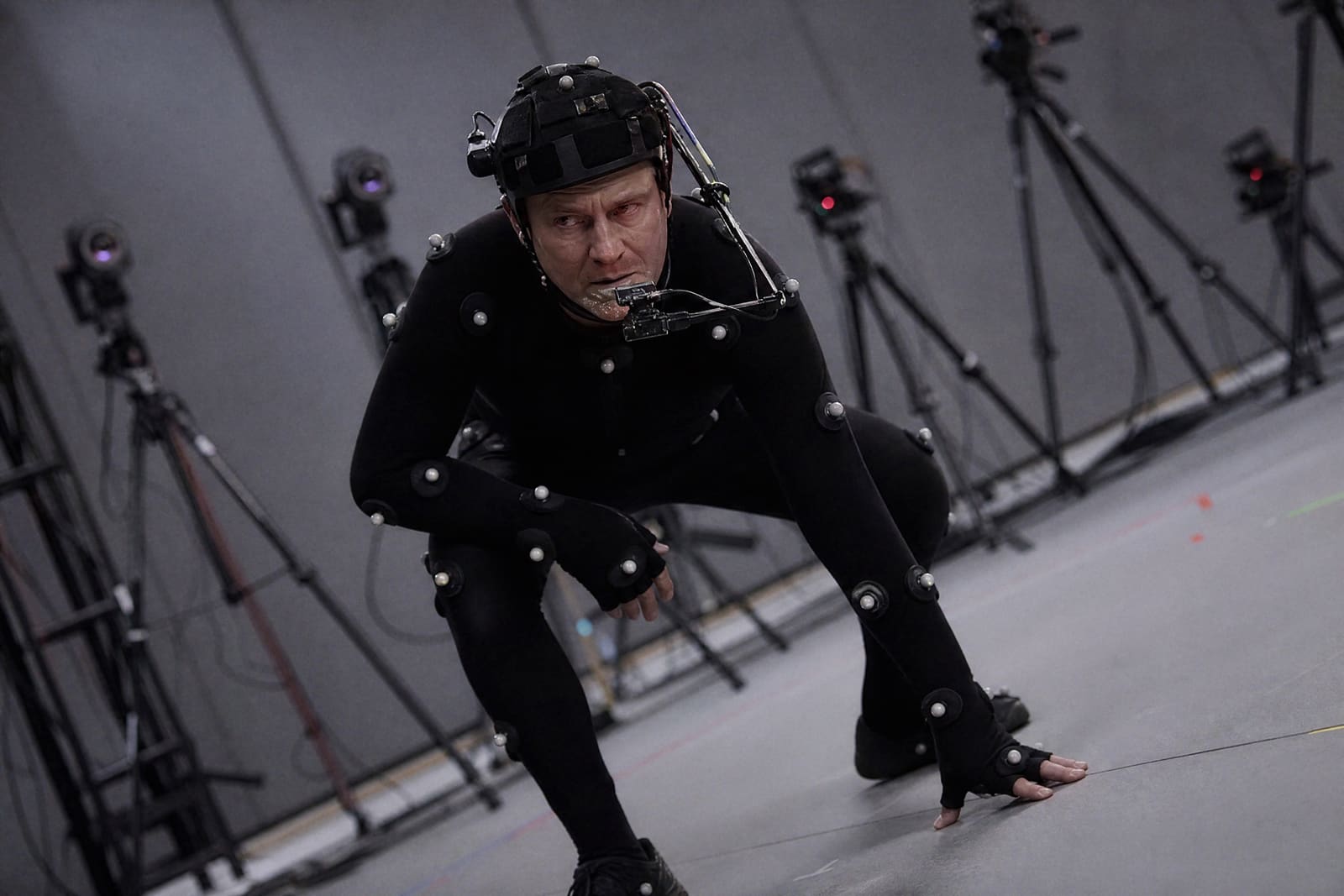 Actor con traje de captura de movimiento y casco con cámara en un estudio rodeado de cámaras