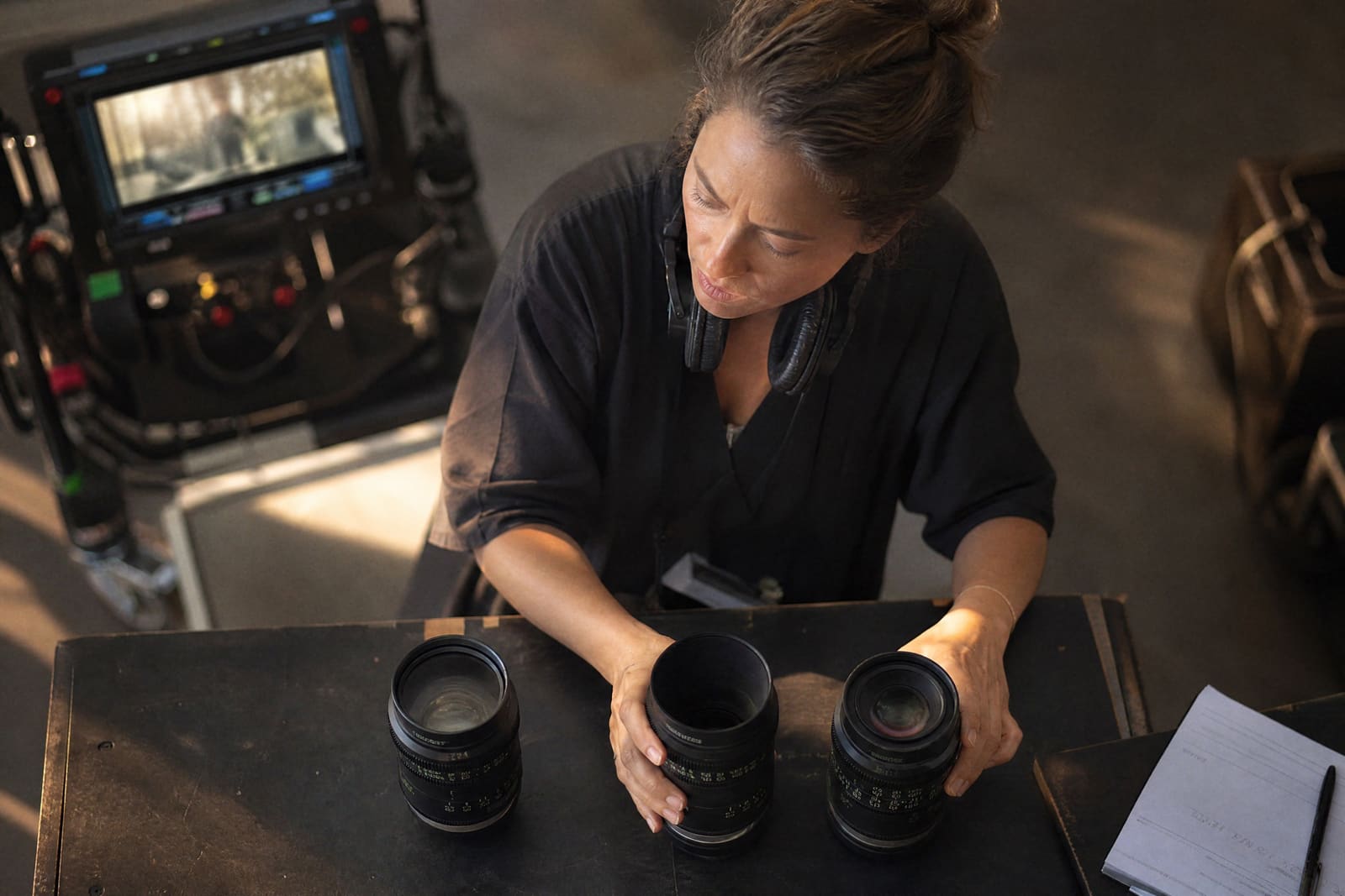 Una directora de fotografía elige entre tres objetivos de cine sobre una mesa de rodaje