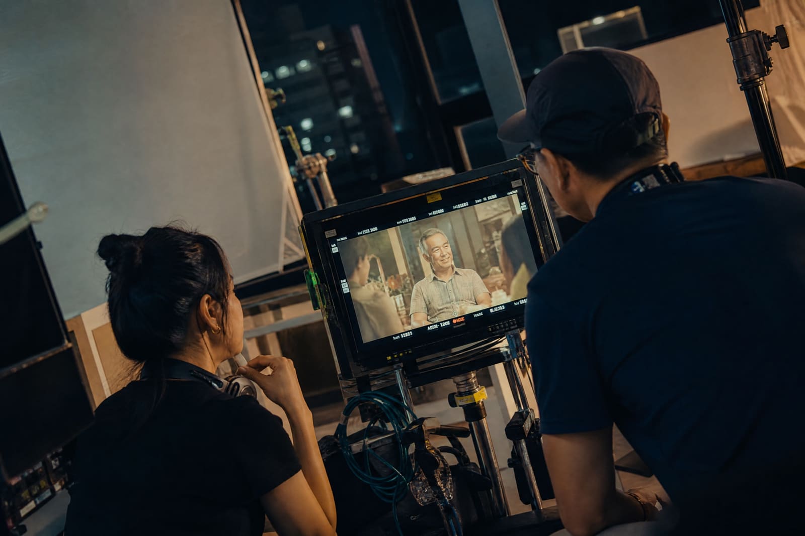 Una directora y un director de fotografía revisan una toma en el monitor durante un rodaje nocturno