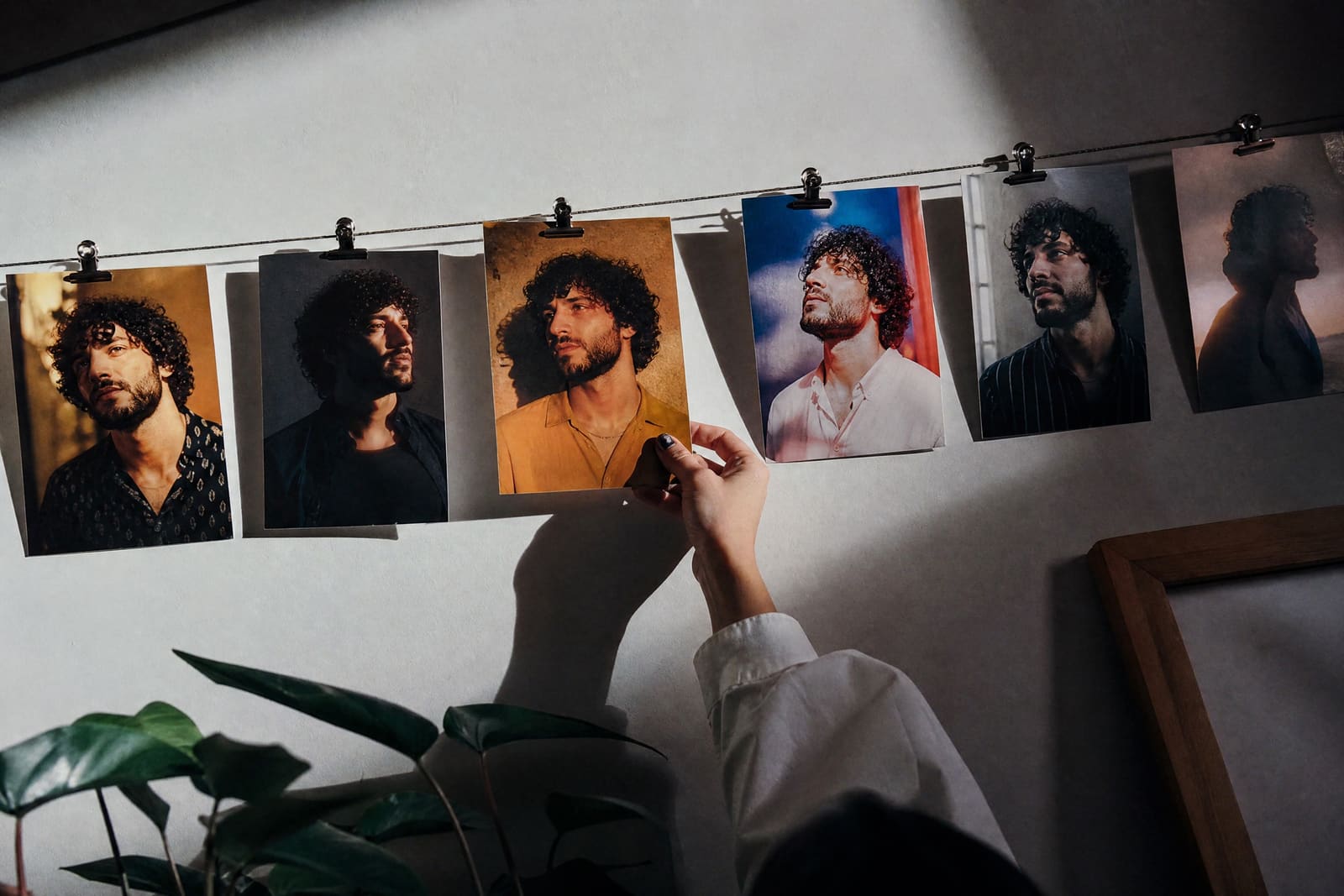 Fotos impresas del mismo cantante en distintos decorados colgadas con pinzas de un cable
